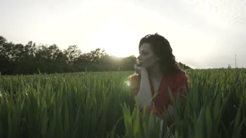 Side view portrait of a beautiful brunette woman in red dress on green field. 動画素材 131226652