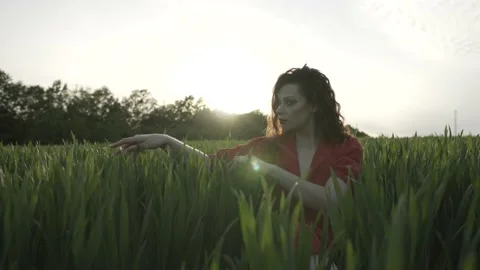Side view portrait of a beautiful brunette woman in red dress on green field. 動画素材 131226656