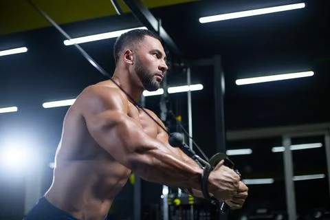 Side view portrait of a bodybuilder working on his chest muscles with cable Stock Photos