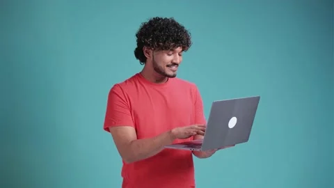 Side view portrait of cheerful Indian man with beard in coral t-shir working on Stock Footage 238684099