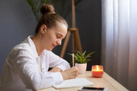 Side view portrait of dark haired attractive woman writing notes in paper not Stock Photos