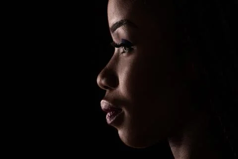 Side view portrait of dark skinned model on a black background. Stock Photos