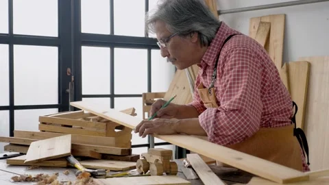 Side view, portrait of dedicated Asian senior male carpenter making furniture Stock Footage 147868727