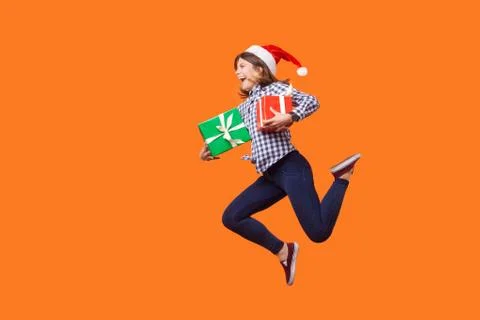 Side view portrait of extremely joyous brunette woman in santa hat jumping or Foto stock