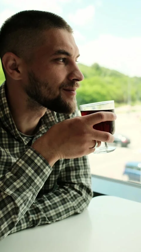 Side view portrait of a man drinking a dark beverage from a glass in a cafe. He Stock Footage 316145033