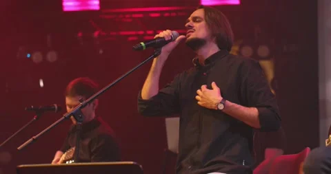 Side view portrait of a man singing to microphone on light background. Stylish Stock Footage 154277858