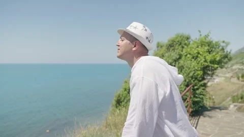 Side view portrait of a man in white looking at the sea outdoors Видео 200519086