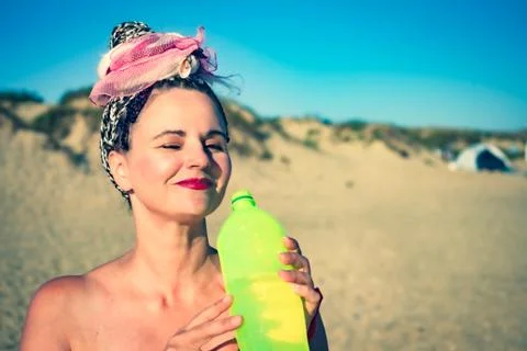 Side view portrait of middle-aged woman drinking a vegetable soda in a bottle Stock-Fotos