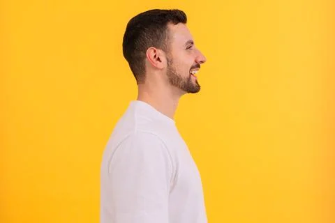 Side view Portrait of a smiling man in white t-shirt against yellow background. Stock Photos