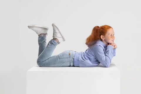 Side view. Portrait of smiling red-headed girl in casual clothes isolated on Stock Photos