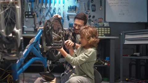Side-view portrait of young caring skillful man teaching cute little son to Stock Footage 232494635