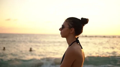 Side view of pretty brunette woman in black bikini walking near the sea on Stock Footage 85198053