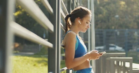 Side view on pretty smiled Caucasian woman in sporty style and airpods tapping Stock Footage 125108203