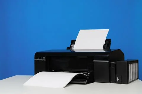 Side view of a printer and a blank sheet of A4 paper on a blue background. Foto stock
