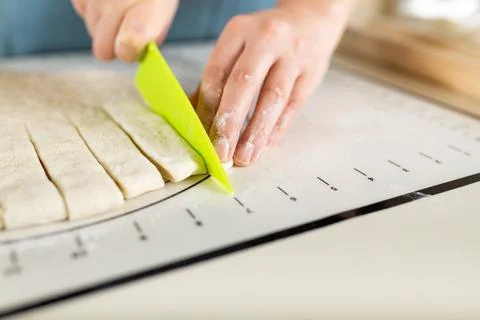 Side view on process of cooking from wheat dough on a kitchen mat with markings Stock Photos