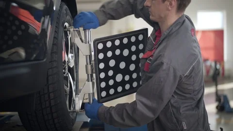 Side view of professional Caucasian man using wheel alignment machine in repair Stock Footage 124603078