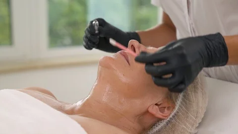 Side view of a professional cosmetologist using cotton bud to cover patients Stock Footage 114504452