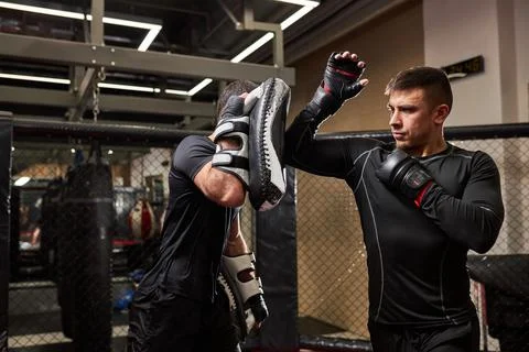 Side view on professional mma fighter teaches self-defense tricks, showing it to Stock Photos