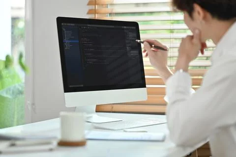 Side view of professional software developer working with coded data in bright 库存照片