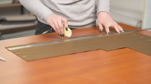 A side view of a professional tailor making a pattern with chalk on brown piece Stock Footage 105476235