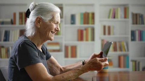 Side view profile of smiling happy senior elderly woman having video chat on Stock Photos