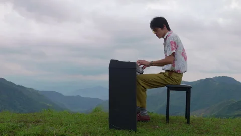 Side View Profile of Vintage Asian Male Musician Playing Piano on Mountain Peak Stock Footage 340400093