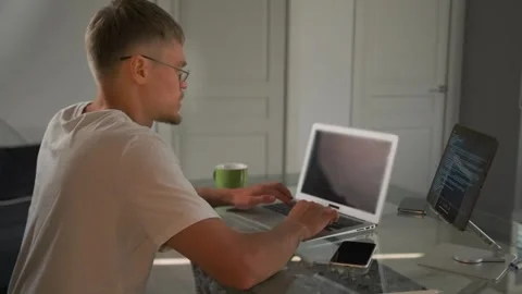Side view. Programmer in glasses joins meeting, updates code and reviews docs. Stock Footage 299893584