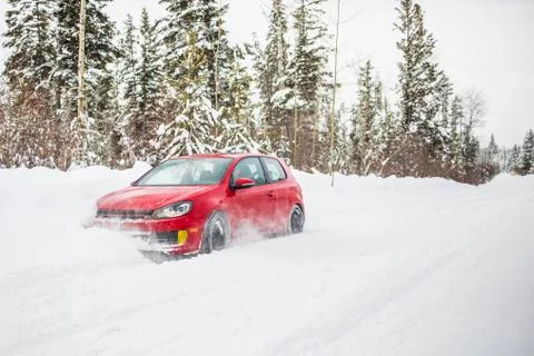 Side view of red car driving on snow covered road. Stock Photos