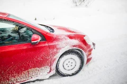 Side view of red car driving through snow storm. Stock Photos