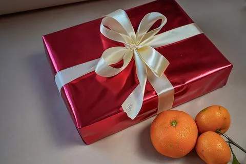 Side View of Red Gift Box with Bow and Tangerines on Beige Background Stock Photos