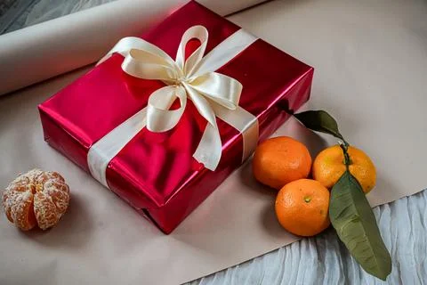 Side View of Red Gift Box with Tangerines on Beige Background Foto stock