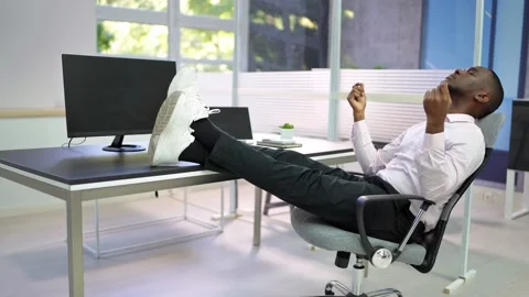 Relaxed man sitting at desk in office looking at computer screen