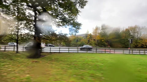 Side view of road traffic through moving vehicle window in fall 스톡 동영상 256150070