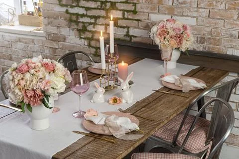 Side view of romantic cute table decor with glasses flowers and lit candles. Stock Photos