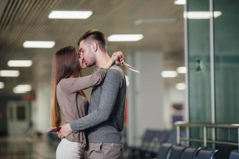 Side view of romantic young couple kissing at airport Stock Photos