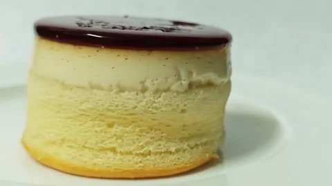 Side view of a round caramel custard pudding cake on a white plate. 스톡 동영상 345338831