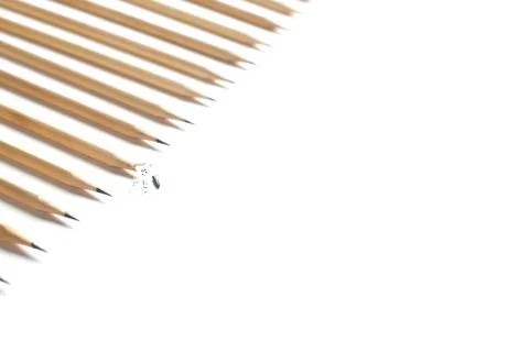 Side view of row of even beautiful sharpened pencils lying on white table Stock Photos