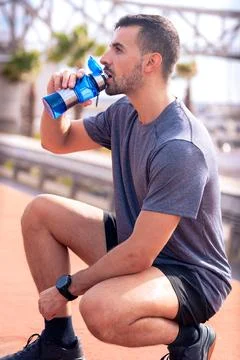 Side view runner man drinking water from a sports bottle outdoors.Vertical Foto stock