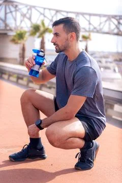 Side view runner man drinking water from a sports bottle outdoors. Foto stock