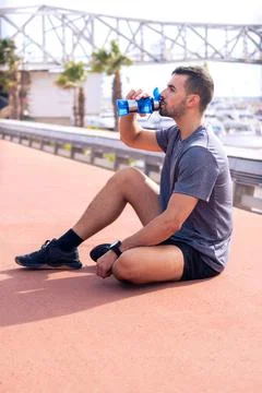 Side view runner man drinking water from a sports bottle outdoors.Vertical Stock-Fotos