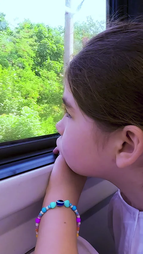 Side view of a sad and bored young girl looking out the window of a moving Stock Footage 338397405