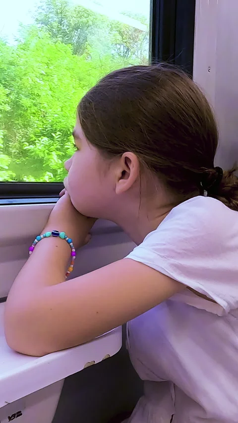 Side view of a sad and bored young girl looking out the window of a moving Stock Footage 338397599