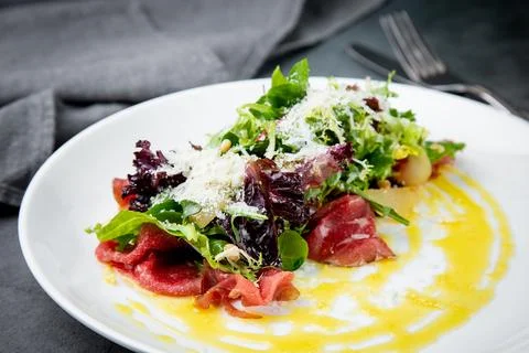 Side view of salad with red fish, herbs and cheese on a white plate Stock Photos