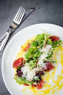 Side view of salad with red fish, herbs and cheese on a white plate Stock Photos