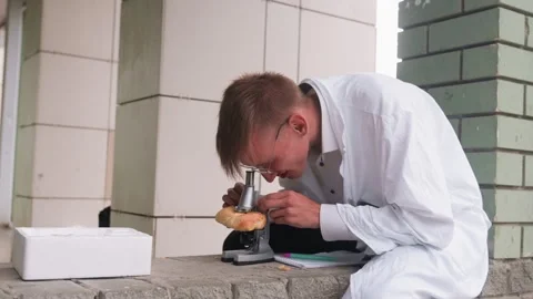 Side View of Scientific Researcher Examining Pastry Through Microscope 스톡 동영상 321115560