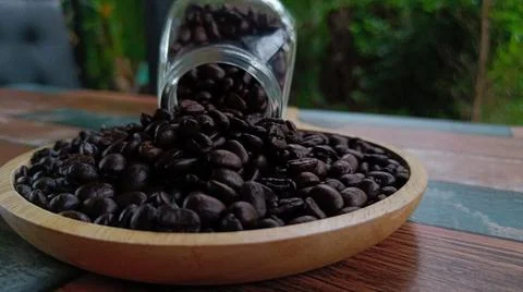 Side view selective focus coffee beans on wooden plate blurred background Stock Photos