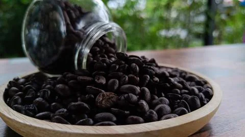 Side view, selective focus, coffee beans in glass jar on wooden plate, blurre Foto stock