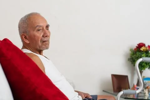 Side view of senior man seated on couch showing relaxed posture and visual .. Stockfoto's
