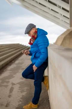 Side view of senior man using smart phone while leaning on retaining wall Stock Photos