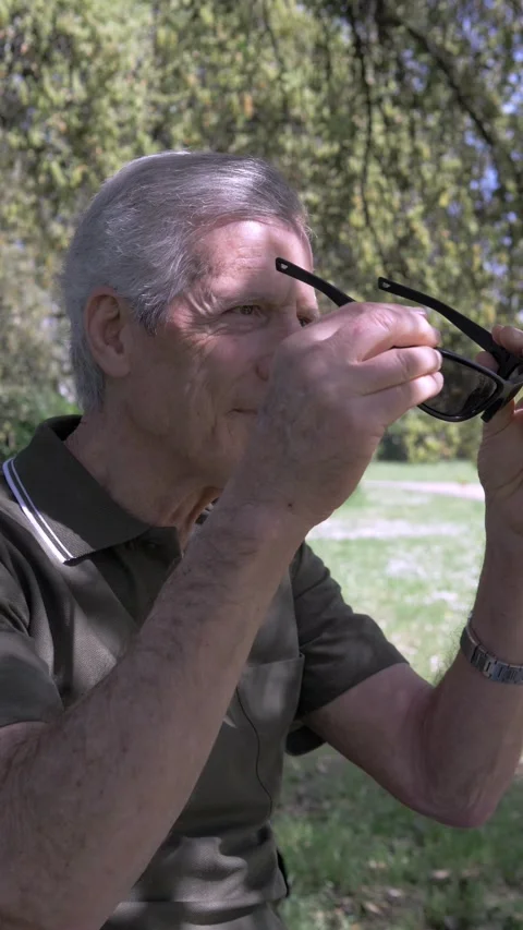 Side view of senior with Parkinson putting on sunglasses with tremor 動画素材 333195021